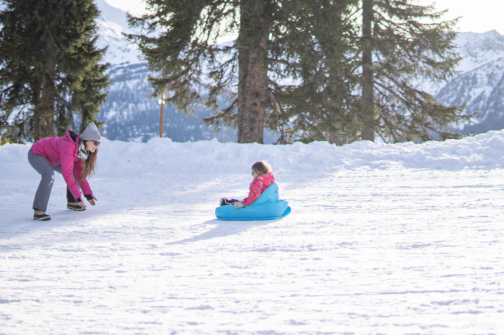 Faire de la luge en famille et partager des instants riches d'émotions pendant les vacances à la neige